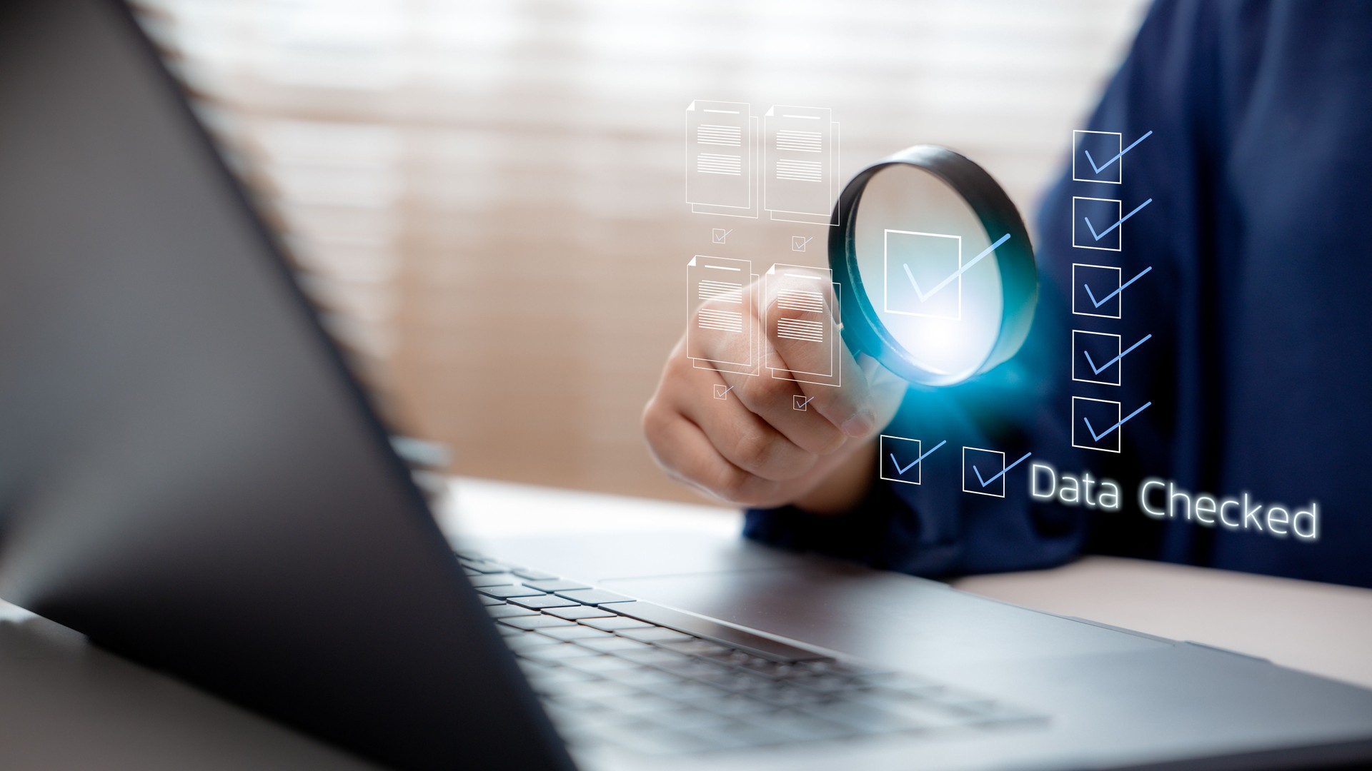 Hand using a magnifying glass over digital documents with checklist marks and a Data Checked label, symbolizing digital checklist, data verification, and quality control in business systems.