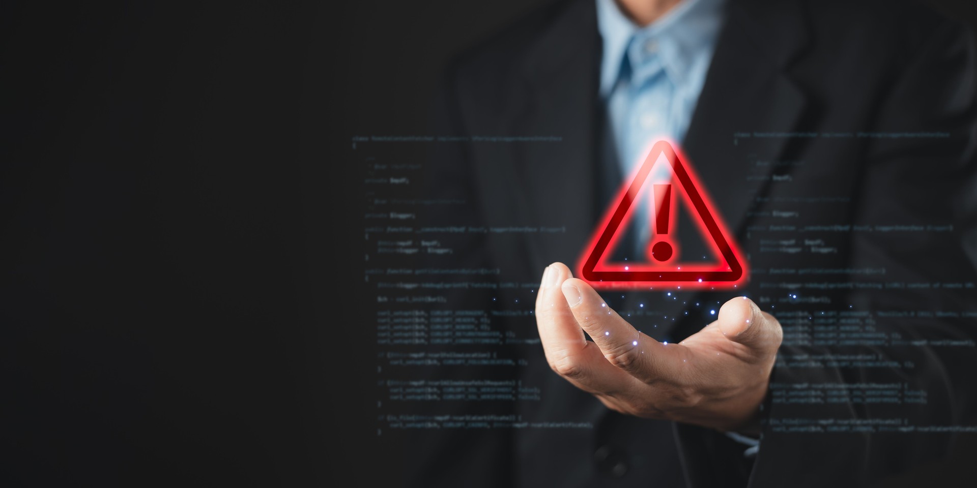 A businessman holds a glowing red warning triangle with an exclamation mark, symbolizing alert, caution, and cybersecurity threat in digital systems, with code elements in the background.